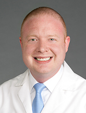 head shot of Caucasian male in white coat and blue tie