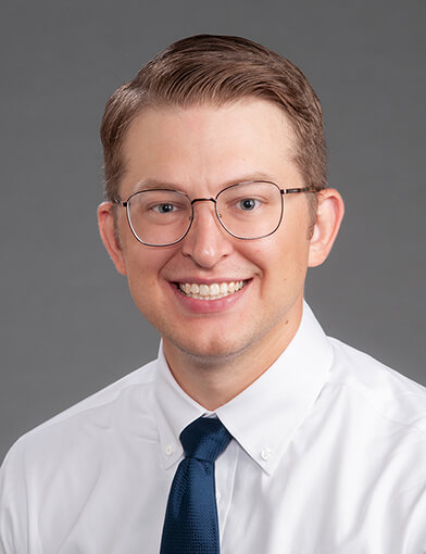 A man with glasses smiling at the camera.