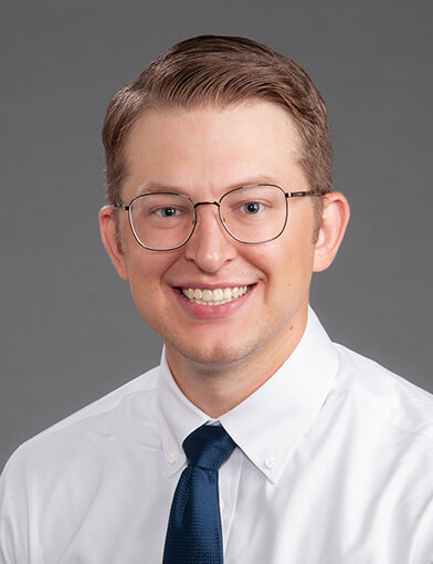 A man with glasses smiling at the camera.