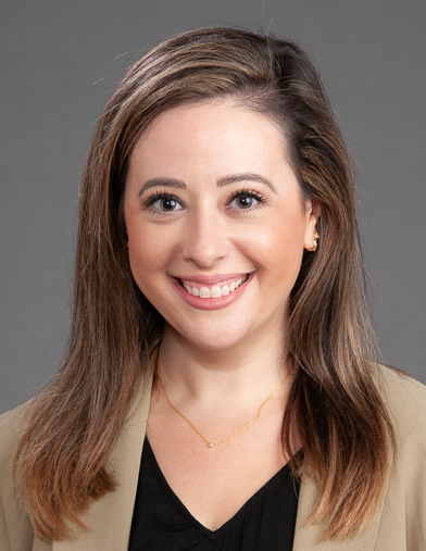 A woman wearing a brown jacket smiling at the camera.