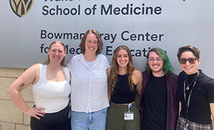 The 2025 fellows standing together outside by a building sign.
