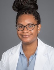 Young African American woman with hair in a bun on top of her head, wearing glasses and white coat