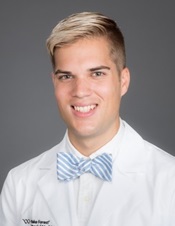 Young man with blond hair wearing a blue bowtie and white coat