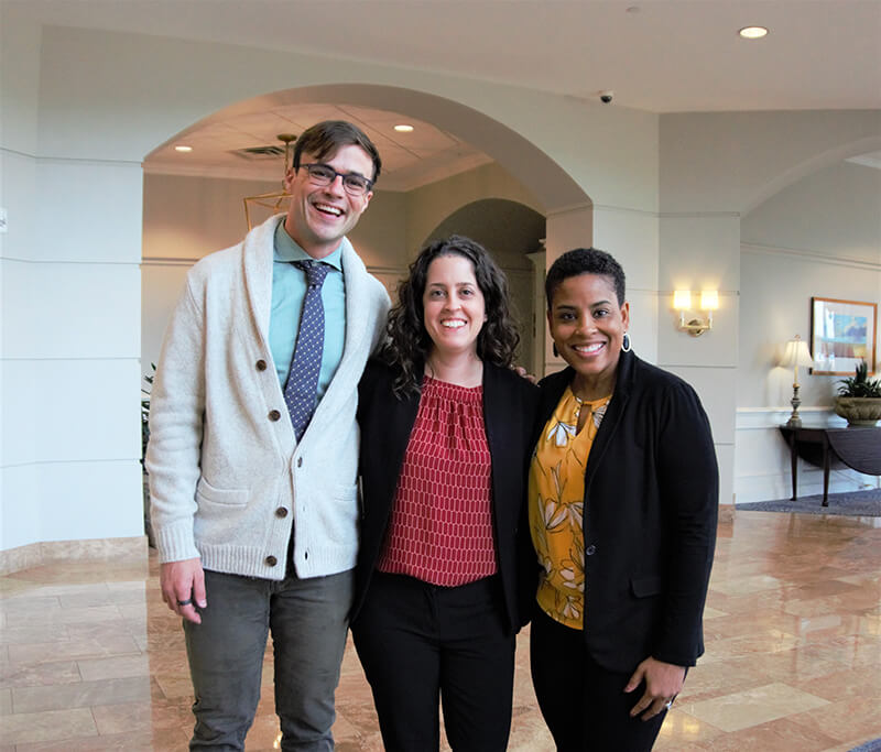 One man and two women standing side by side and smiling at the camera.