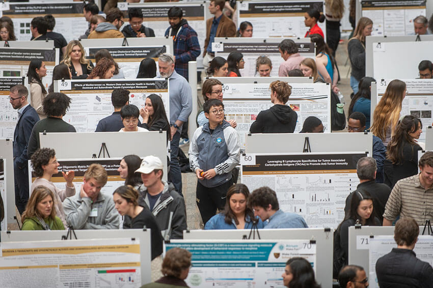 A large group of grad students looks at the many posters at the Annual Research Day.