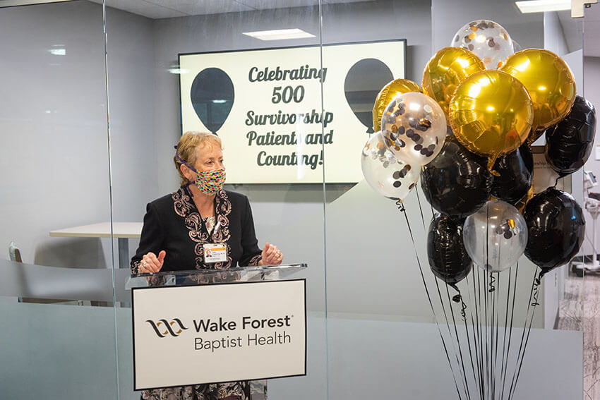 A woman in professional attire stands at a podium to give a presentation at the Annual Research Day.