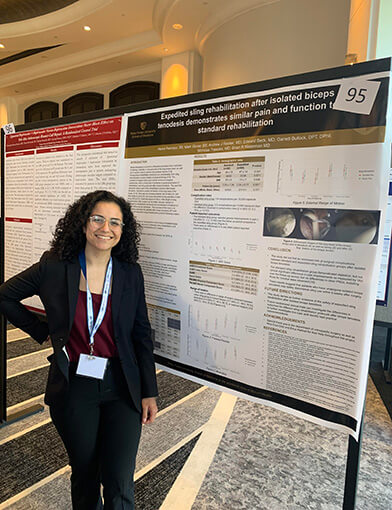 Alexis Restrepo stands next to posters of her ersearch.