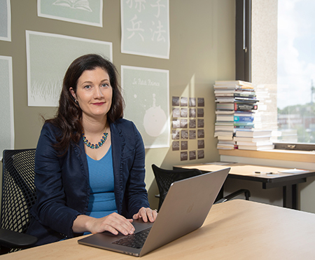 Meredith Adams, MD, associate professor of anesthesiology, looks at the camera as she sits as a desk with her laptop open