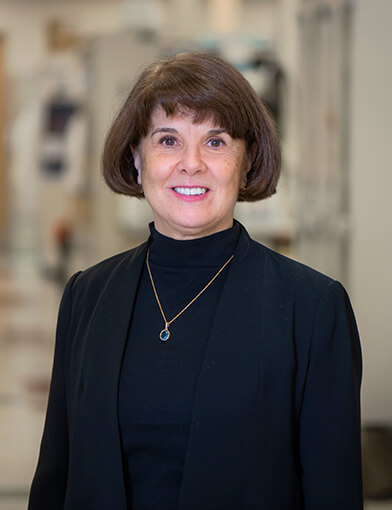 An older woman wearing a dark sweater and smiling at the camera.