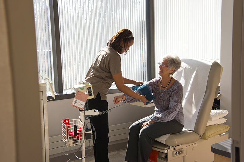 A nurse checking the blood pressure of an elderly woman.