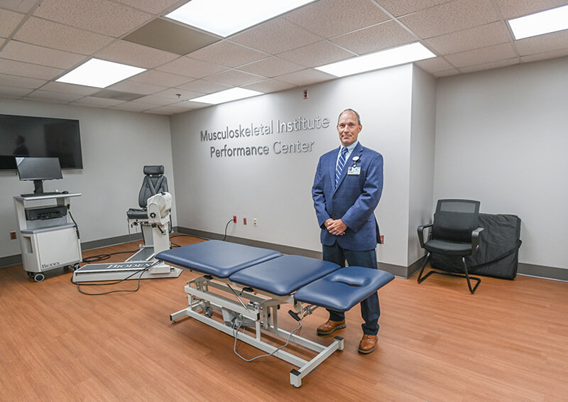 A man standing behind a medical gurney.