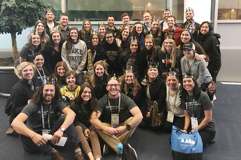 Group photo of Wake PA students and faculty sitting on ground, all wearing black shirts, at 2019 annual AAPA conference in Denver, Colorado