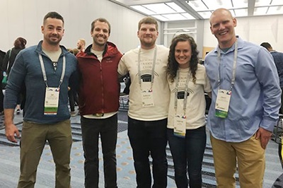 Small group of Wake PA students and faculty stand in hallway, close together and smiling, at 2019 annual AAPA conference in Denver, Colorado