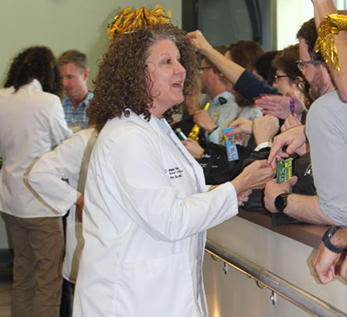 Member of the PA Class of 2020 goes down the line and faculty congratulate her and fill the pockets of her white coat with snacks.