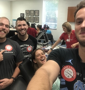 A group of PA students wearing black shirts and blood drive stickers pose for a group selfie