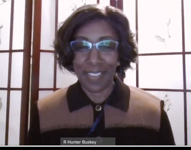 A Black woman wearing glasses appears on a computer screen