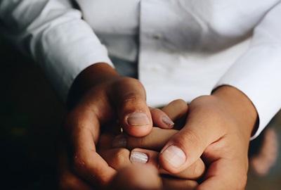 Close-up view of man in white shirt holding unseen person's hand in both of his hands