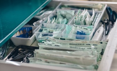 Open drawer with medical supplies such as alcohol swabs, scissors, gloves and bandages