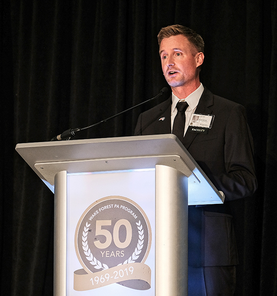 PA alum Erich Grant addresses the crowd from a podium with the 50th anniversary logo on it