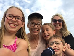 Two women and three children wearing beach attire take a selfie