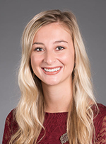 A white woman with long blonde hair smiles for a head shot photo