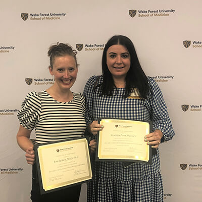 Two women facing the camera holding awards.
