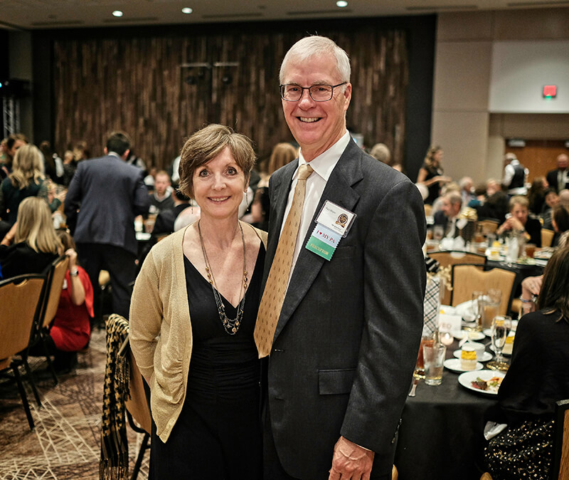 A man and a woman standing side by side and smiling at the camera.