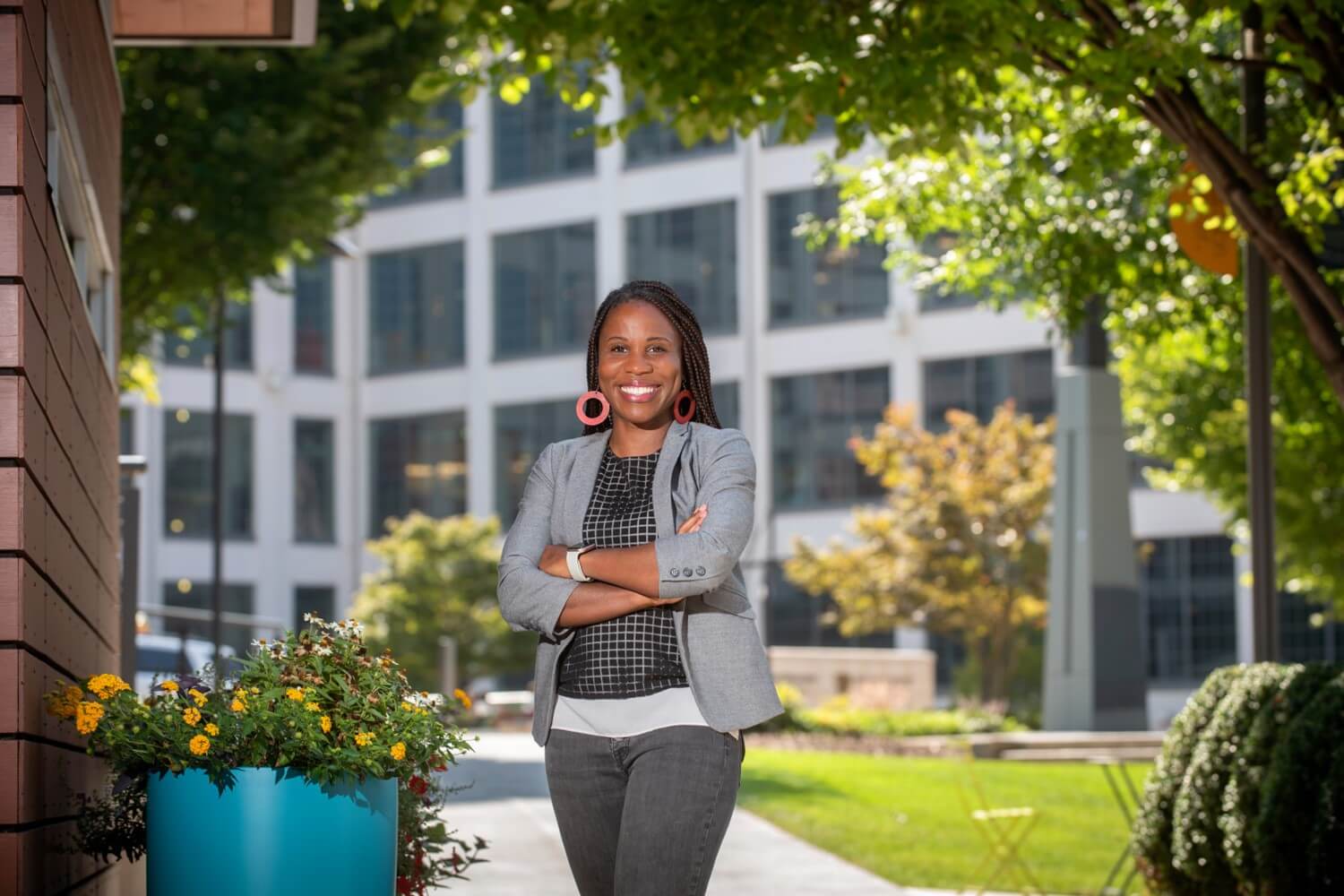 Andrea McKinnond wearing a gray outfit standing with her arms crossed in a courtyard.