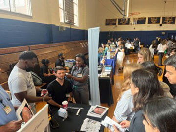 A large gathering at a school gymnasium for an event showing how PAs practice medicine.