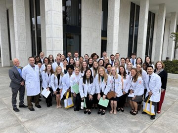 PA students, faculty and practicing PAs taking a group photo together outside of a building.