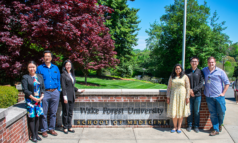 Members of Dawen Zhao's biomedical engineering lab stand in front of a Wake Forest School of Medicine sign