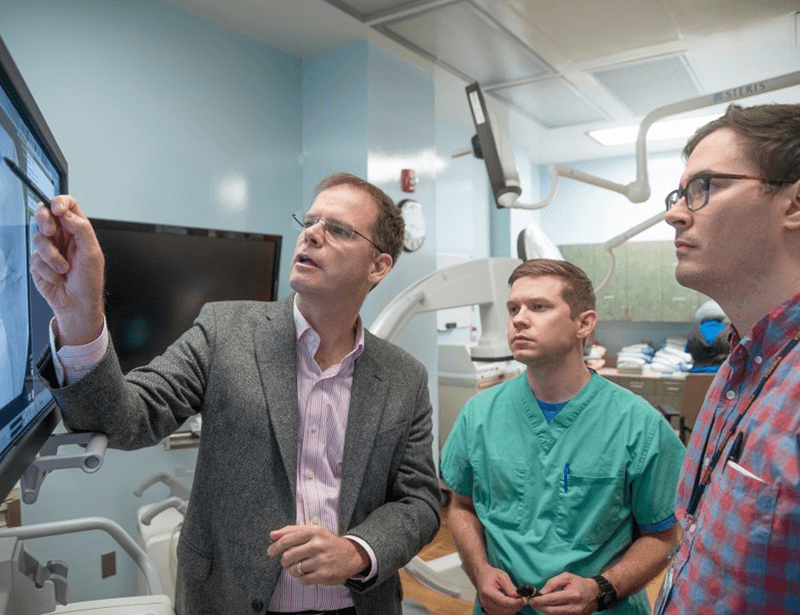 Robert Hurley, MD, PhD, FASA, Executive Director, Pain Service Line showing details of a scan to colleagues.