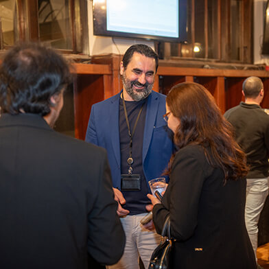 A man in a blue formal jacket smiling and talking with others.