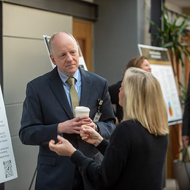 A man and woman in formal attire talking in a large room.