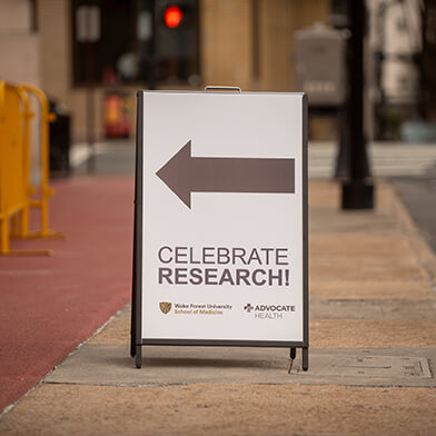 A white sign with a gray arrow on it and the text: "Celebrate Research!".