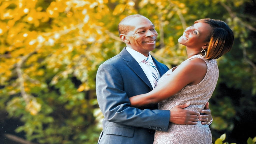 Louis Hall pictured holding his wife as she smiles 