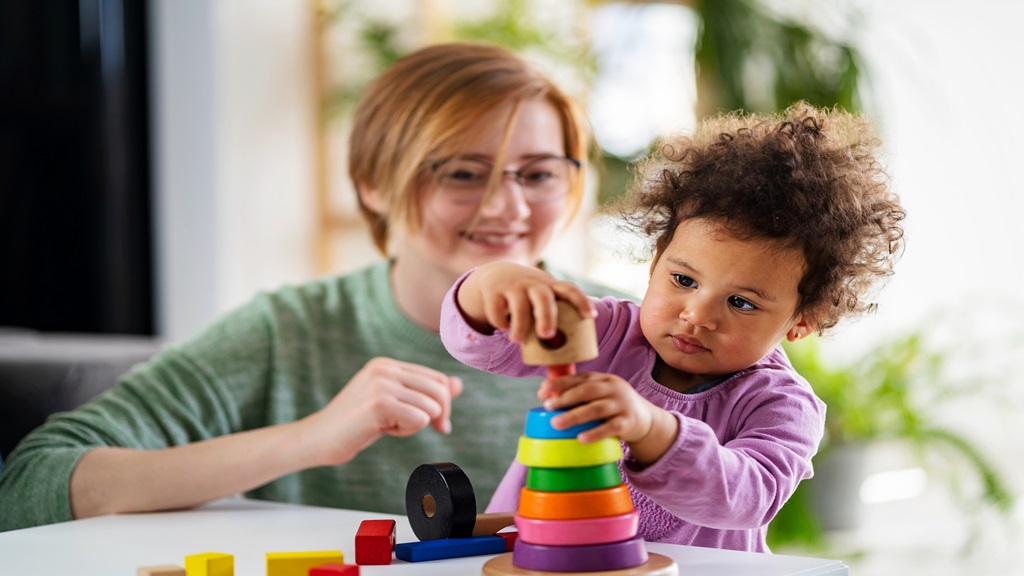 Child playing with toy while adult is watching