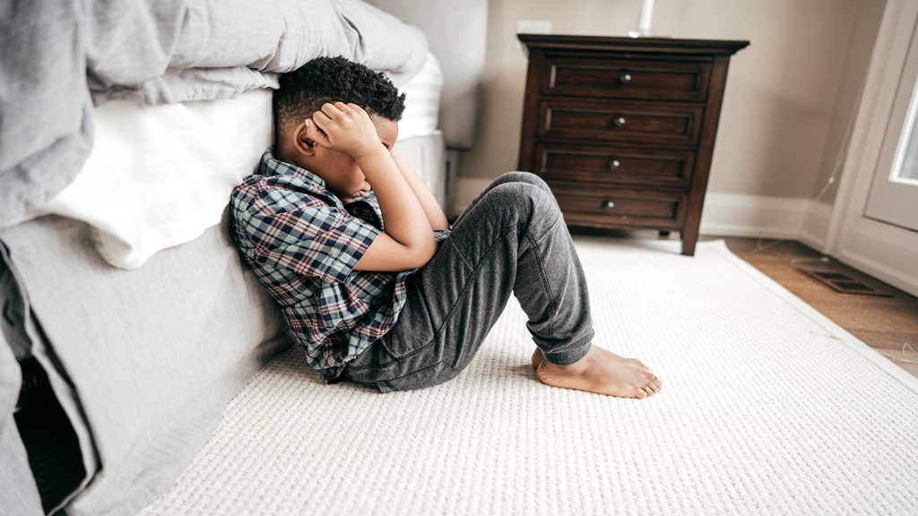 Little boy clenched up by the edge of his bed