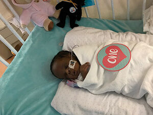 A baby laying in a hospital bed, wrapped in a blanket.