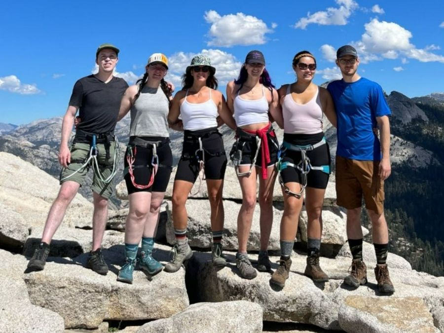 Group of smiling male and female hikers at a mountain peak.