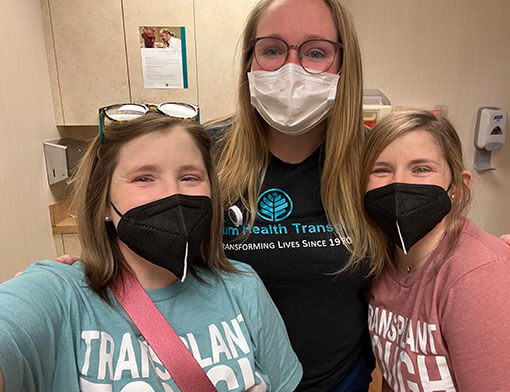 Three girls in casual attire wearing masks at a medical facility.