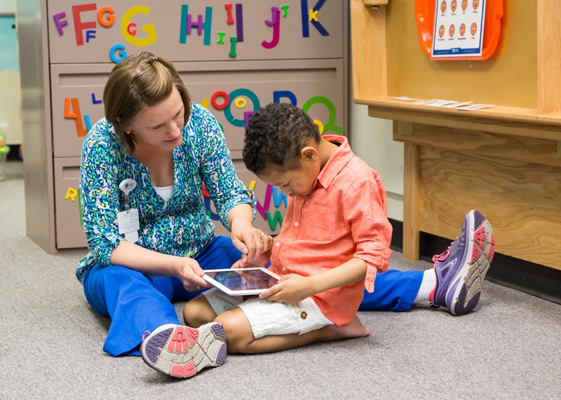 Young boy reading a book with his teacher.