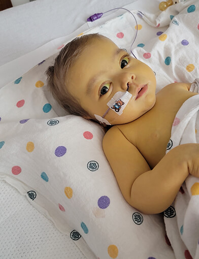 A baby resting on a pillow in a hospital bed.
