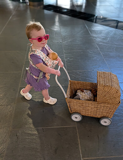 A toddler aged girl playing with a toy stroller set.