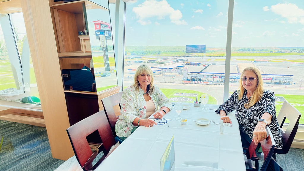 Two women in sitting at a table next to a large window.