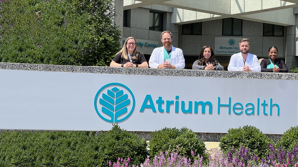 Advanced Practice Providers (APPs) standing by an Atrium Health sign