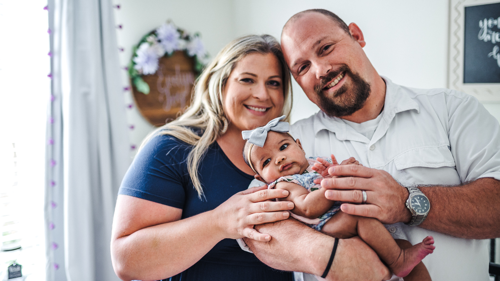 Family photo of Laura and James Cobb holding their adopted daughter, Evelyn