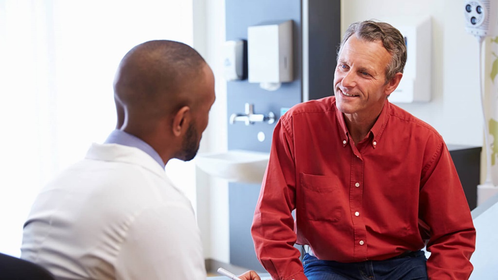 A man in a red shirt and a man in a white shirt talking to each other.