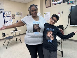 Two people standing in a classroom smiling at the camera.