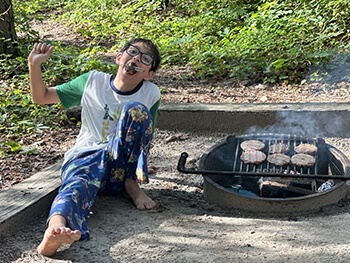 A child eating by a campfire.